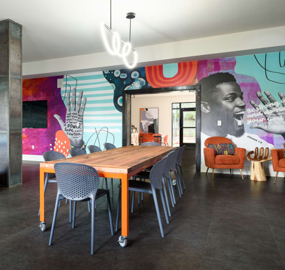 a large wooden table with chairs in a room with a large mural on the wall