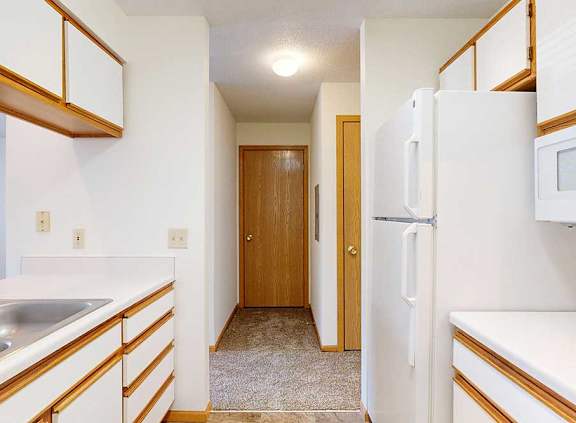 A galley kitchen with white appliances and wooden cabinets