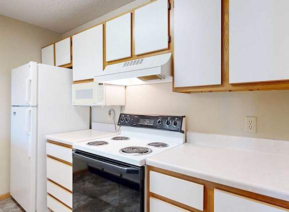 Kitchen with white oven, over-the-range microwave, refrigerator, and ample cabinet storage.