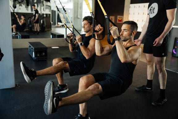two men in a gym using ropes on a swing