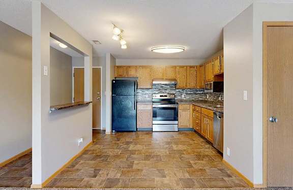 a kitchen with wooden cabinets, upgraded appliances, tile backsplash, and a windowed accent wall by the front entry