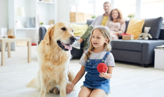 a little girl sitting on the floor with a dog