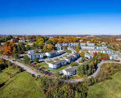 An aerial view of a large building complex surrounded by trees in autumn colors.