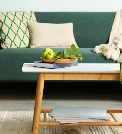 a living room with a green couch and a coffee table with a bowl of fruit  at Lexington on the Green, Raleigh