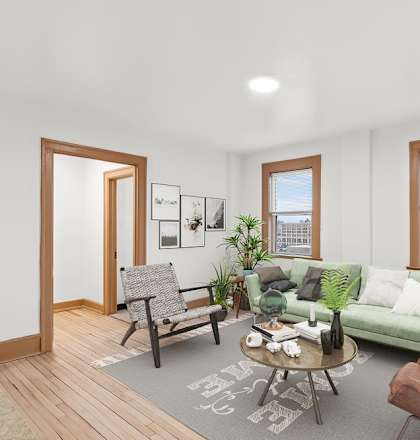 A living room with a green couch, a chair, a coffee table, and a rug.