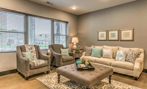apartment living room with two chairs, a couch, and large windows