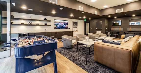A foosball table is in the middle of a living room with a couch and a chair.