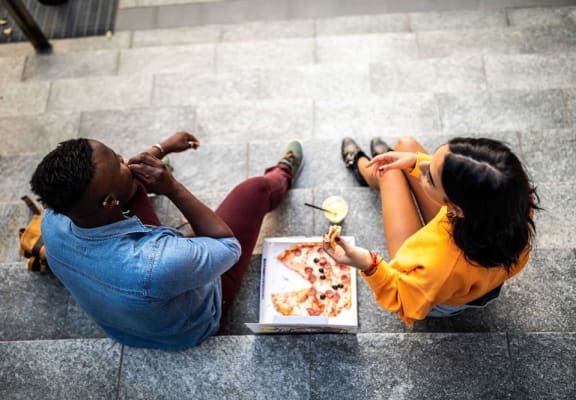 Couple eating pizza at Residences at The Streets of St. Charles Apartments in  Missouri, 63303