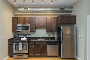Gale Lofts Kitchen with Stainless Steel Appliances, Granite Countertops, Track Lighting, and Mocha Wood Cabinets