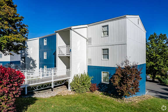 a white and blue house with a white deck and a blue sky