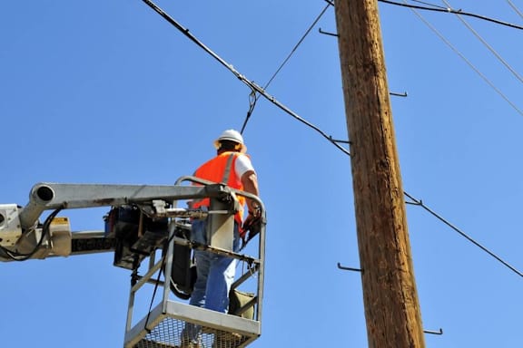 A worker in a cherry picker is repairing a power line.