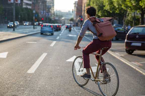a man riding a bike down a city street with a backpack on