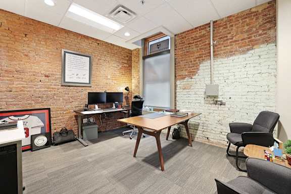 a conference room with a brick wall and desks and chairs