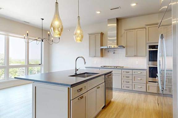 Penthouse apartment kitchen with taupe cabinets, a large island, and premium stainless appliances