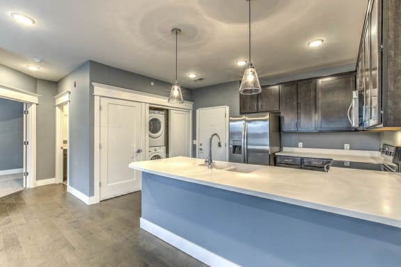 large apartment kitchen with pendant lighting, brown cabinets, and white counters