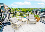 Thumbnail 7 of 13 - Two chairs and a table are on a balcony.