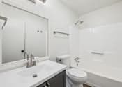 Thumbnail 7 of 15 - A white bathroom with a sink, toilet, and bathtub.