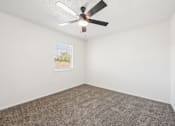 Thumbnail 10 of 15 - A room with a ceiling fan and carpeted floor.