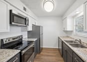 Thumbnail 8 of 15 - A kitchen with a black stove top oven and a black microwave.