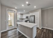 Thumbnail 32 of 83 - A modern kitchen with a white island and stainless steel appliances.