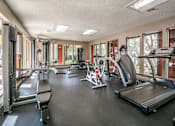 Thumbnail 22 of 27 - Fitness center with treadmills and weight training machines at The Colony Apartments, Universal City, Texas