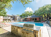 Thumbnail 4 of 27 - Pool area with outdoor grill and lounge seating at The Colony Apartments, Texas
