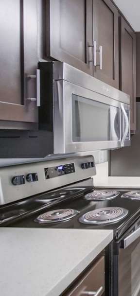 A modern kitchen with dark brown cabinets and stainless steel appliances.