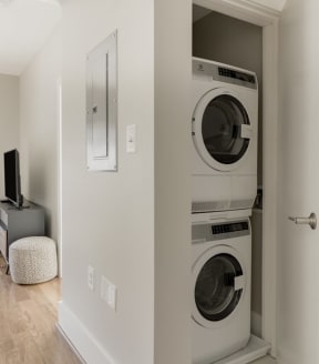 a living room with a washer and dryer and a tv on a stand
