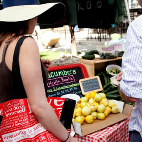 a woman holding a box of lemons at an outdoor market