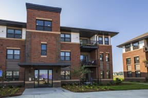the front of a brick apartment building with a sidewalk