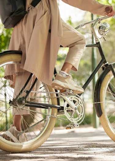 A person in a beige coat is riding a bicycle.