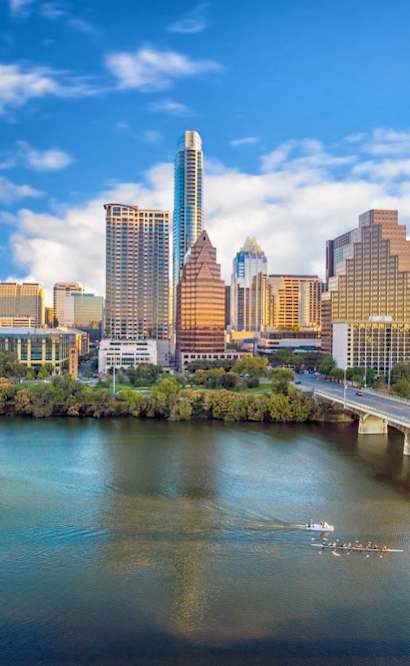 A cityscape with a river in the foreground and a bridge crossing it.