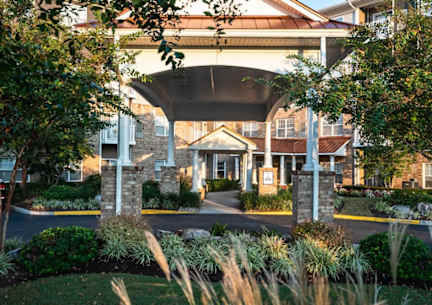 A building entrance is framed by a white archway and flanked by stone pillars.