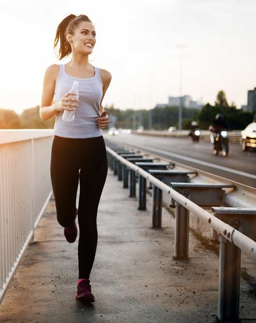 A woman is running on a bridge holding a water bottle.at Icon Apartments, Arizona