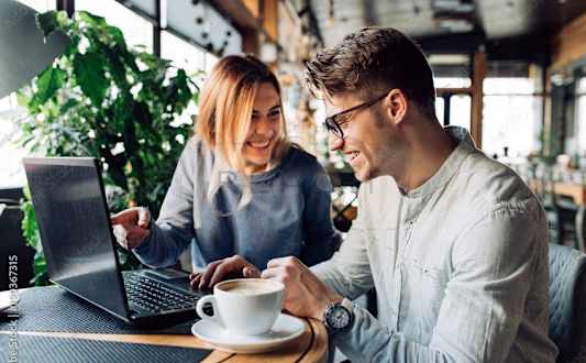 Two people are sitting at a table with a laptop and a cup of coffee at Rivercrest Apartments, Piscataway , NJ, 08854