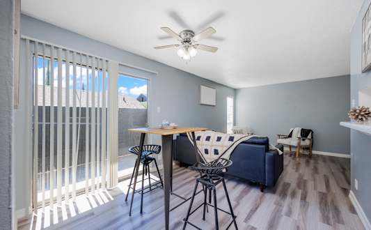 A living room with a blue couch and a dining table with chairs.