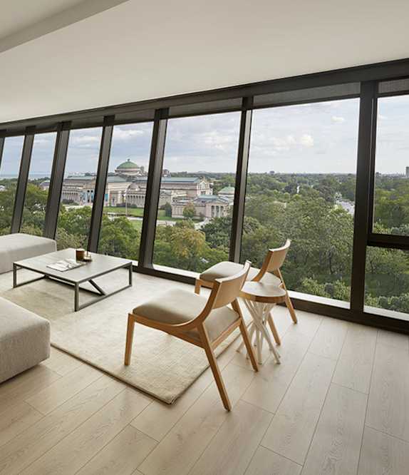 A living room with a couch, chairs, and a view of the city.