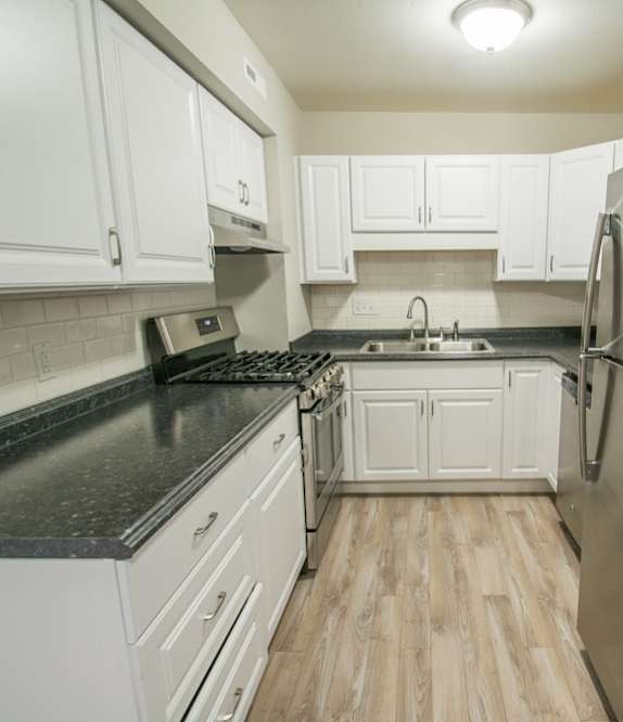 A kitchen with white cabinets and a black counter top.