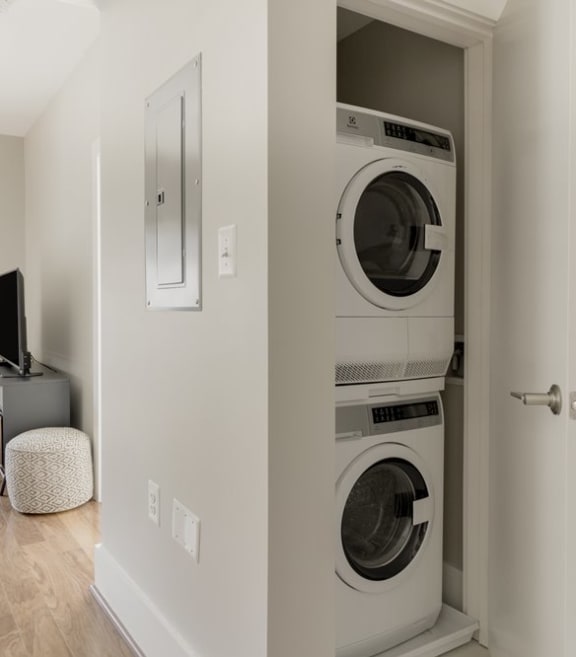 a living room with a washer and dryer and a tv on a stand