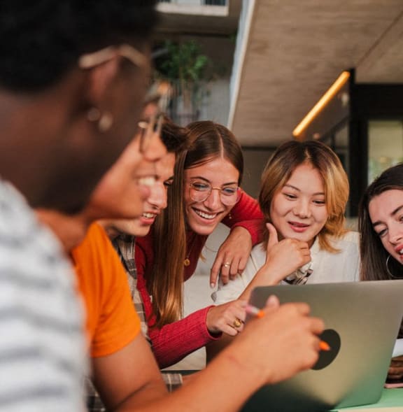 a group of girls laughing while looking at a laptop computer