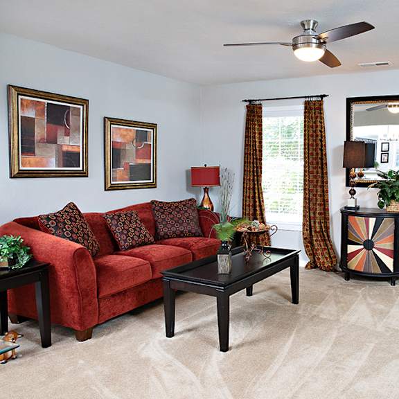 A living room with a red couch and a black coffee table.