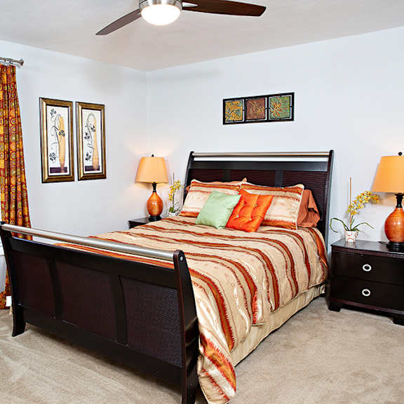 A bedroom with a bed, chair, and two lamps.