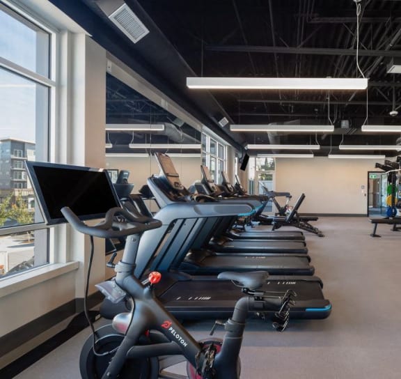 a gym with treadmills and other exercise equipment in a room with a window