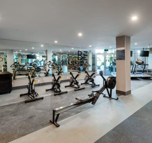 a gym with treadmills and other exercise equipment in a room with a window