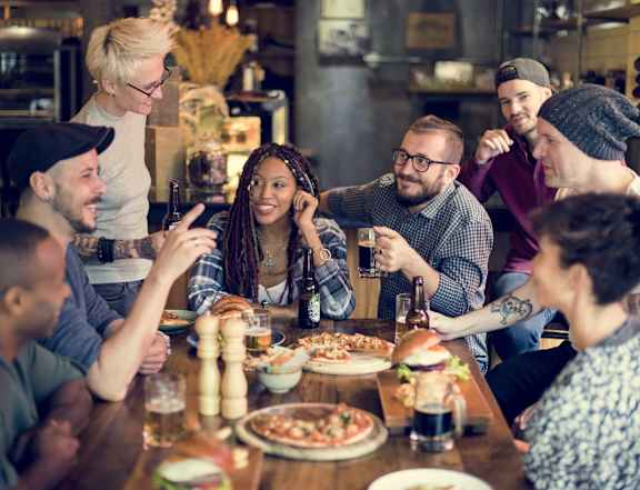 A group of people enjoying a meal and drinks together at a restaurant.