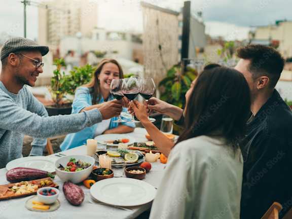 People toasting with wine glasses at a table with food.