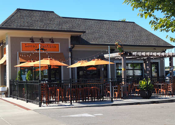 A restaurant named Local Cantina has orange umbrellas outside.
