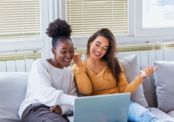 two women sitting on a couch looking at a laptop at The Parker Austin, Pflugerville, 78660