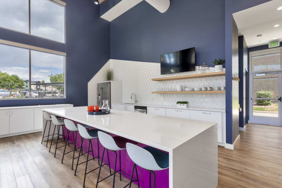 a kitchen with a large white island with a white countertop and purple chairs