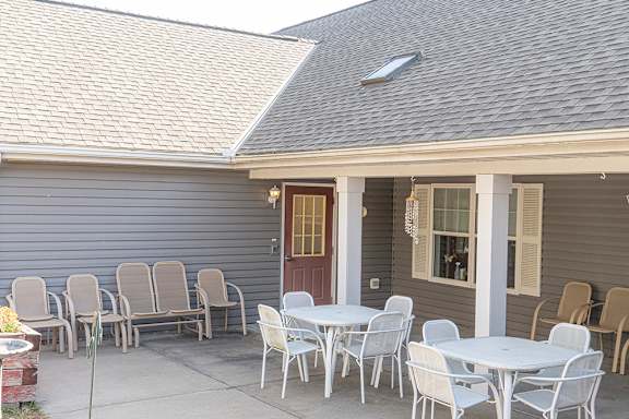 A grey house with a white table and chairs in front.